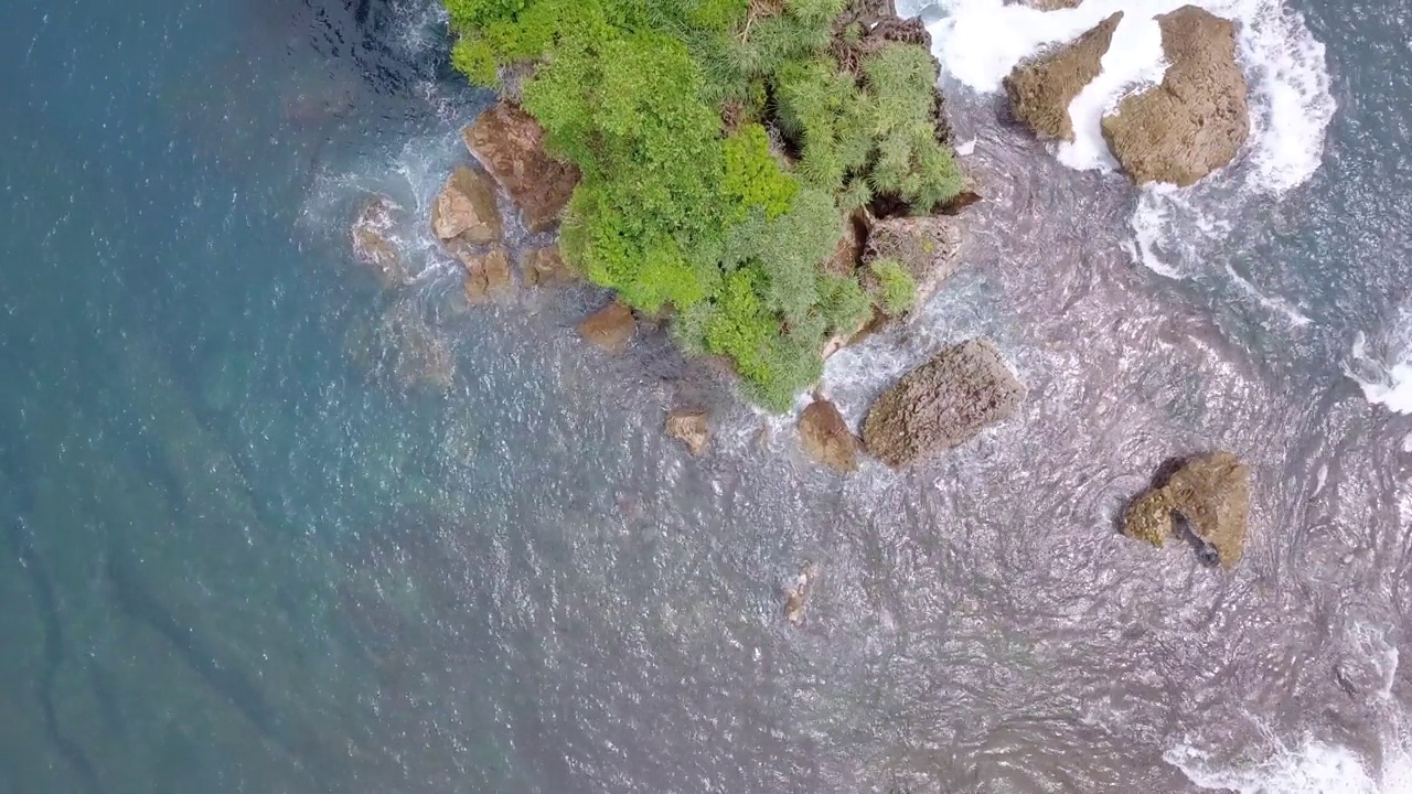 无人机拍摄的珊瑚岛被绿树覆盖，被热带海滩的海浪拍打着。视频素材