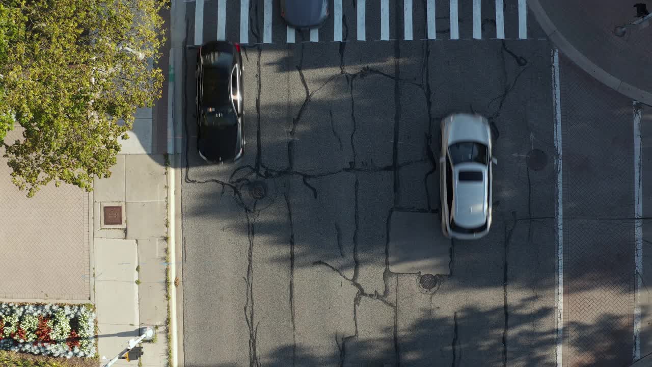 空中的俯仰无人机视图的行人在道路上的交叉。汽车在城市街道上行驶。伊利诺斯州内伯维尔大街上的许多家庭。视频素材