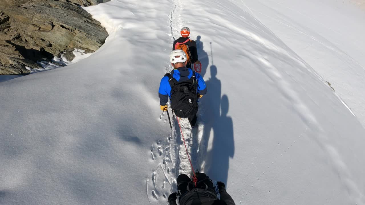 高级登山队正在向欧洲阿尔卑斯山积雪覆盖的山峰进发。使用绳索和攀爬设备视频素材