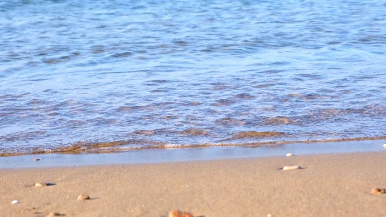 夏日阳光明媚的一天，沙滩上蔚蓝的大海的轻柔波浪视频素材