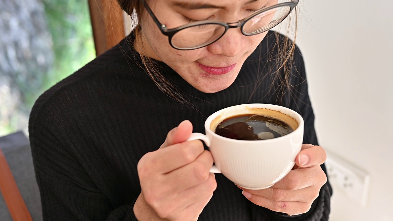 幸福的亚洲女人喝黑咖啡。视频素材