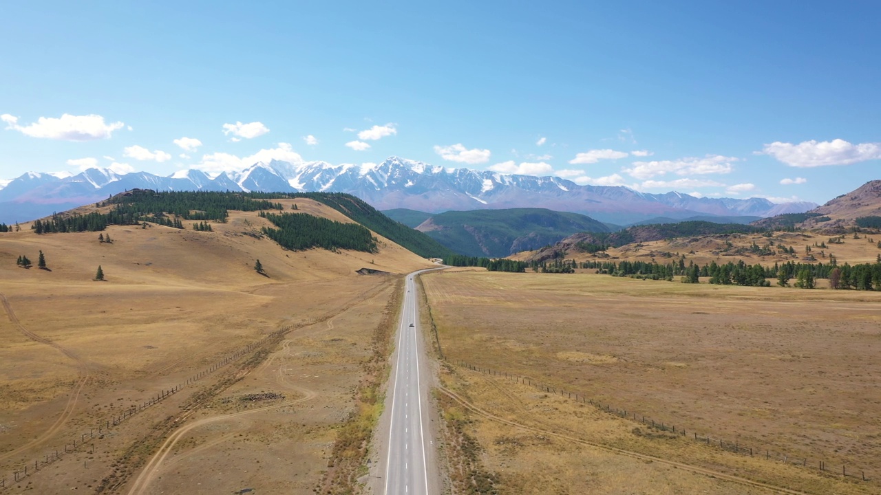 行驶在通往雪山山峰脚下的沥青公路上的车辆视频素材