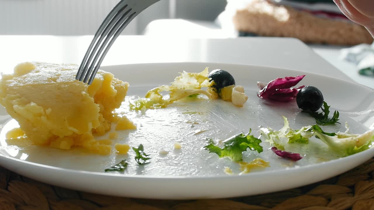 一个女孩用叉子从一个白色的盘子里吃蔬菜沙拉视频下载