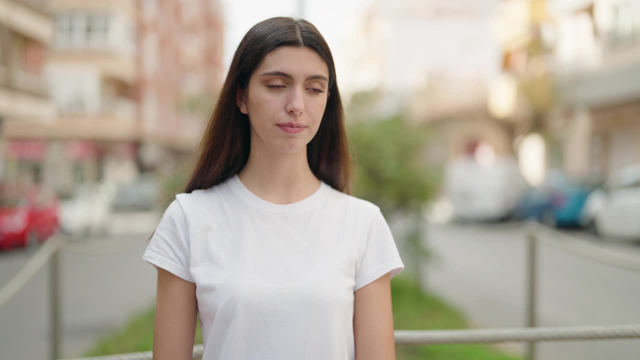 年轻的西班牙女孩微笑着自信地站在街上视频素材