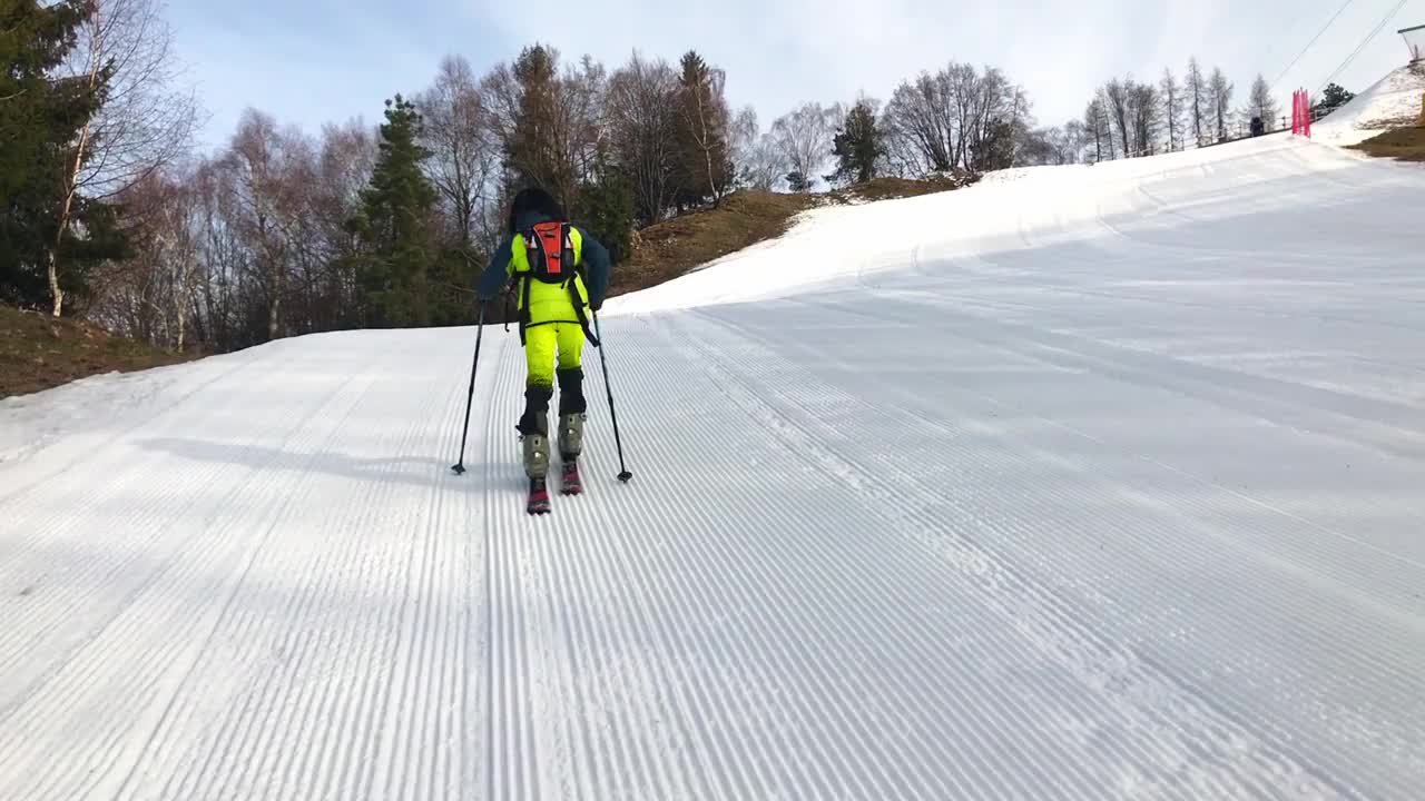 一个小的滑雪登山者在滑雪斜坡上攀登视频素材