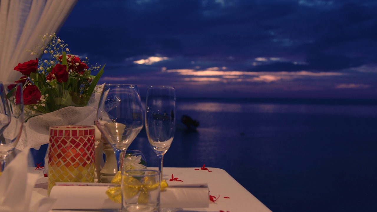 装饰节日的餐桌。表装饰婚礼。浪漫的晚餐会为两人在夕阳下的海滩上美丽的云彩背景视频素材