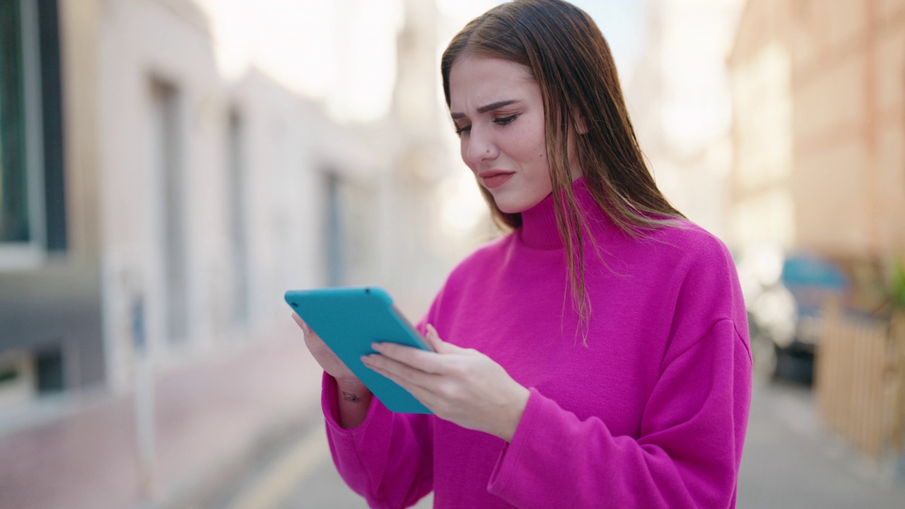 年轻的金发女人在街上用触控板微笑自信视频素材