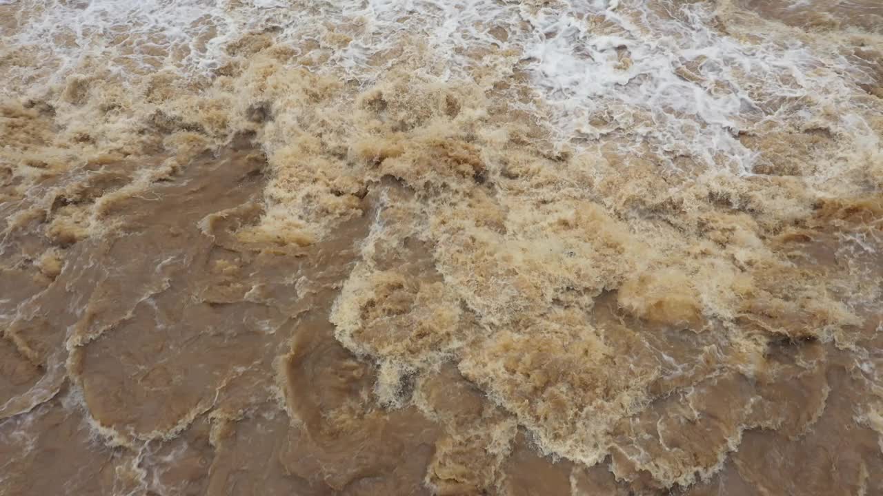 高角度无人机视频快速流动湍流泥泞洪水和淹没草地地区。澳大利亚黄金海岸视频素材