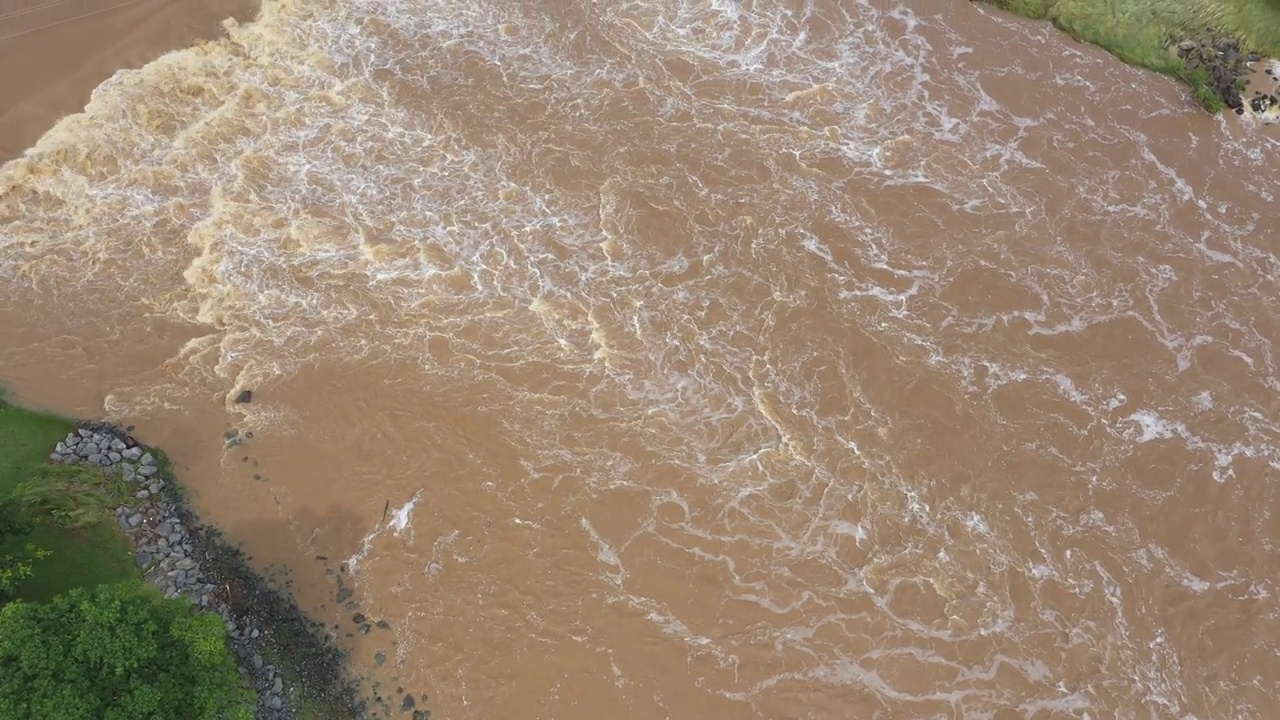 高角度无人机视频快速流动湍流泥泞洪水和淹没草地地区。澳大利亚黄金海岸视频素材