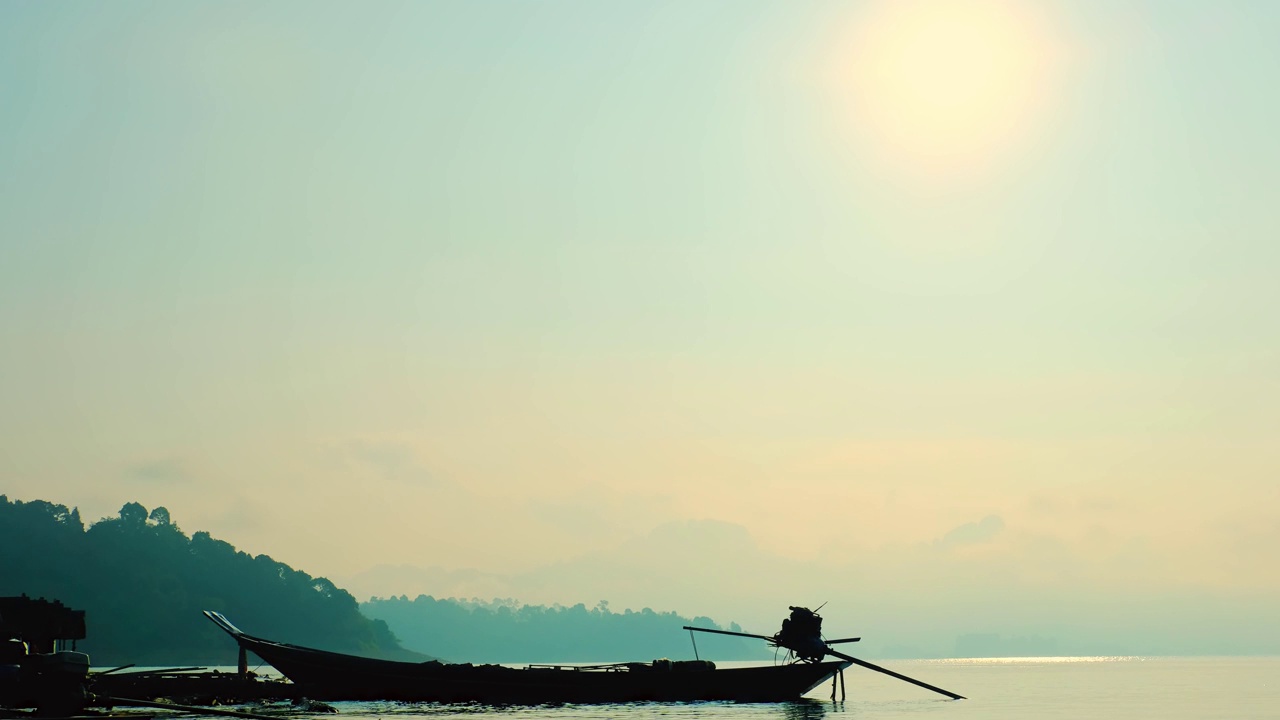 时间推移，泰国苏拉他尼的“周兰坝(Ratchaprapa Dam)”，泰国木制长尾船在阳光的背景下水面上的剪影。视频素材