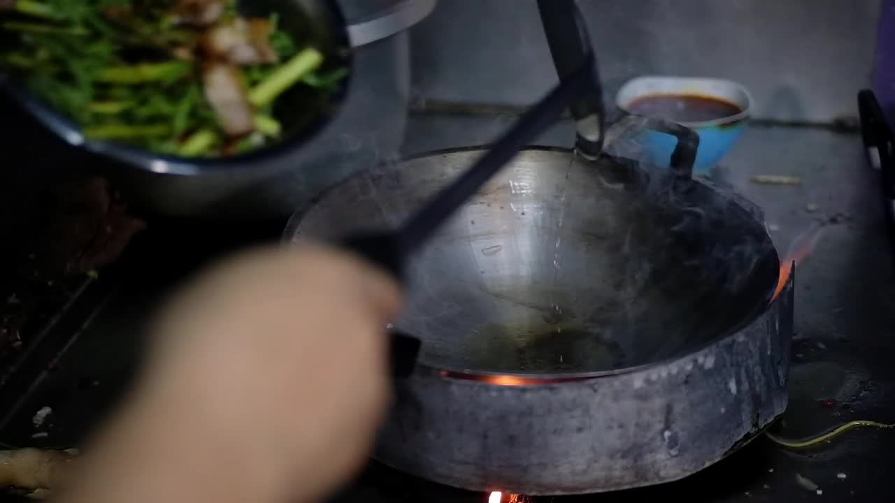 厨师在厨房餐厅用红辣椒煸炒含羞草水，然后在热煎锅里点火，这是泰国传统食物。视频素材