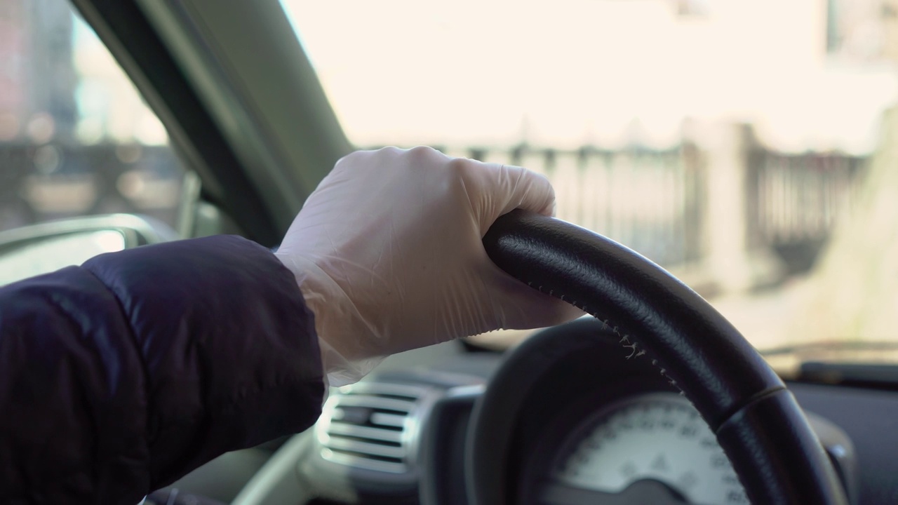 年轻女子戴着防护手套开车。2019冠状病毒病大流行视频下载