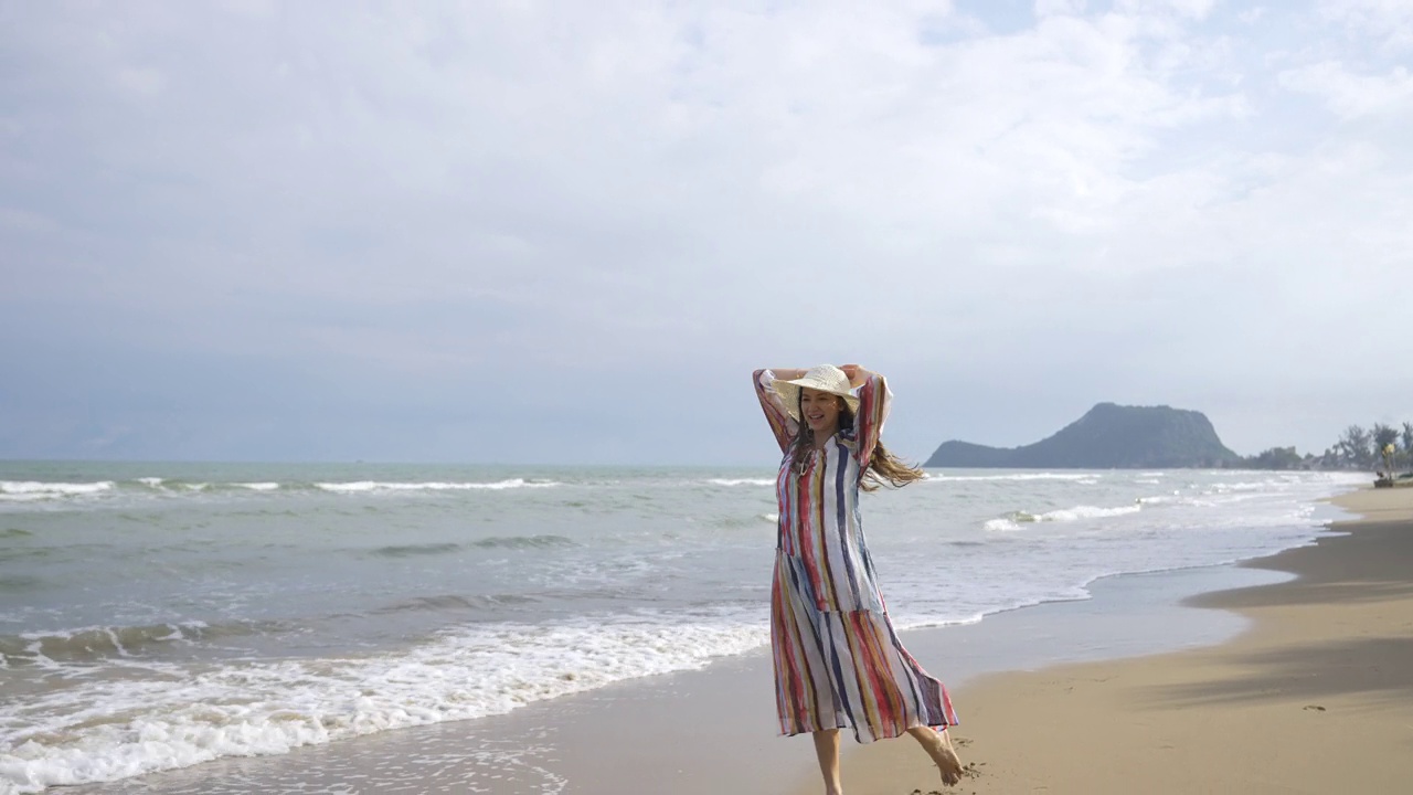 美丽的白人妇女在夏天阳光灿烂的一天走在热带海滩上的4K肖像视频素材