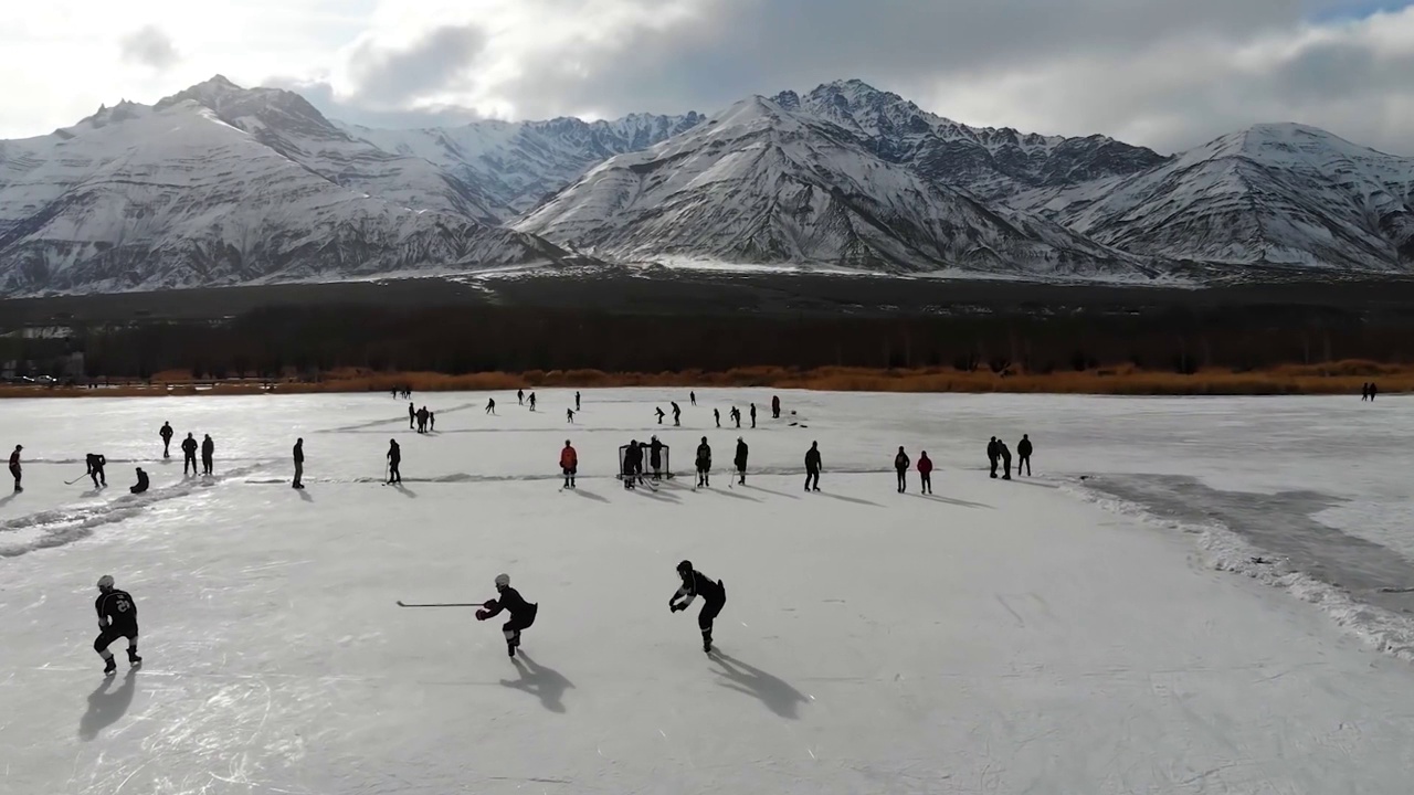 俯视图冰上曲棍球冰场竞技场游戏被雪山包围。视频素材