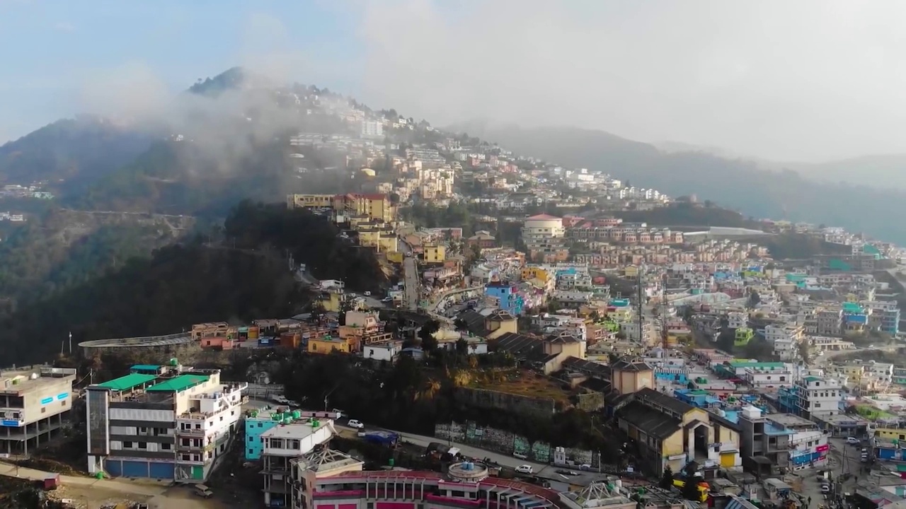 在印度北阿坎德邦的丘陵景观上的喜马拉雅城市鸟瞰图，山上有一条河流流过。无人机的观点。视频素材