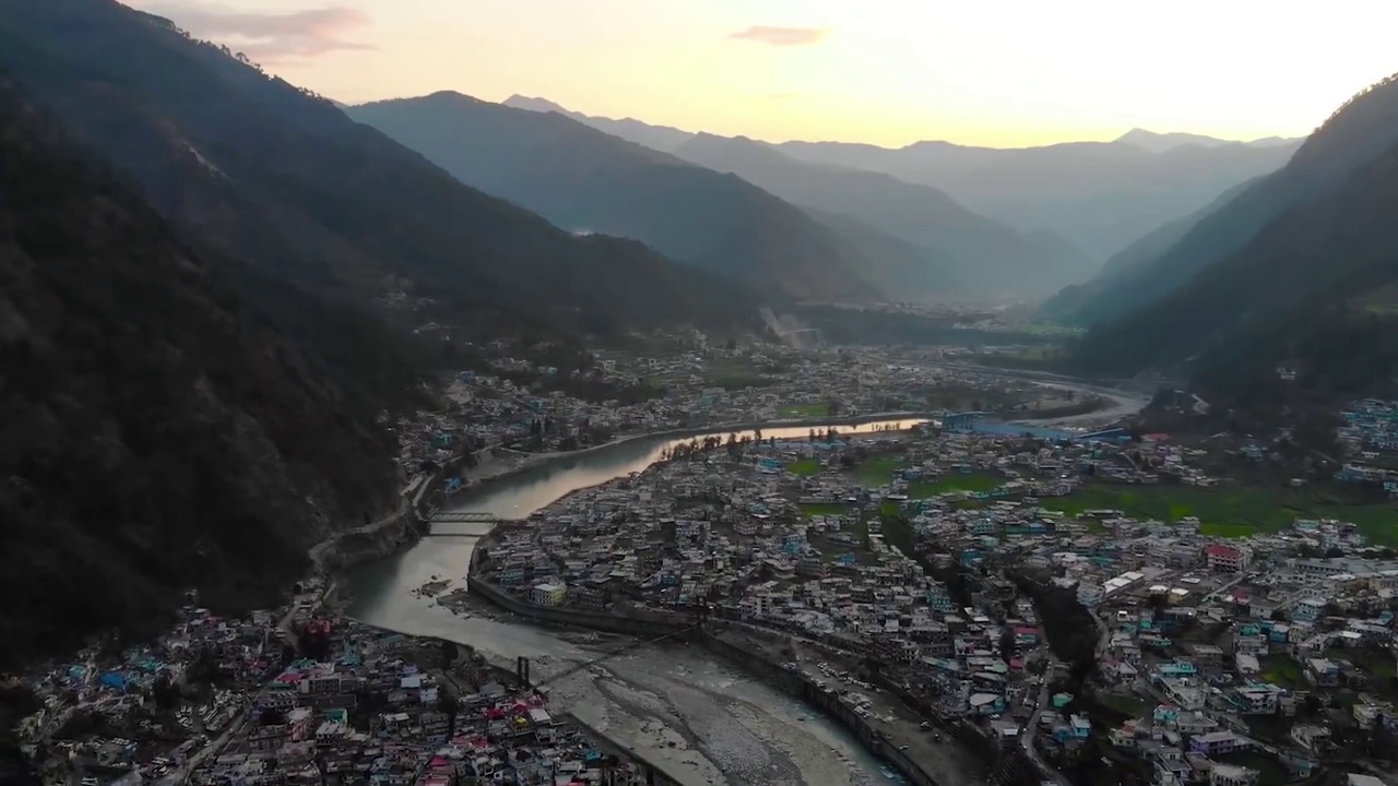 在印度北阿坎德邦的丘陵景观上的喜马拉雅城市鸟瞰图，山上有一条河流流过。无人机的观点。视频素材