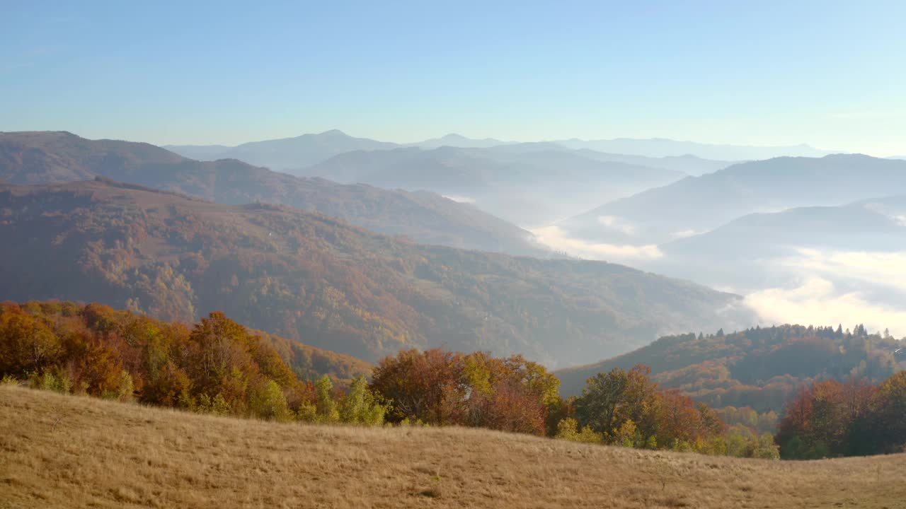 在一个阳光明媚的日子里，一架无人机飞过风景如画的秋山。视频素材