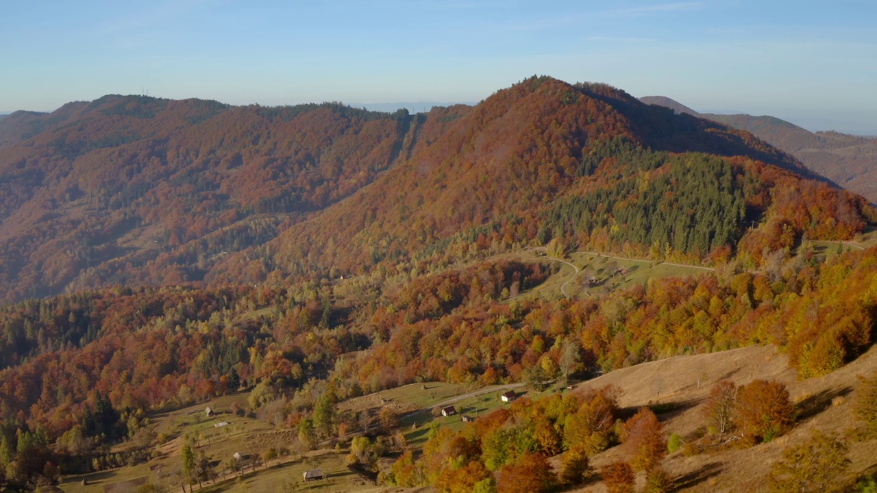 在一个阳光明媚的日子里，一架无人机飞过风景如画的秋山。视频素材