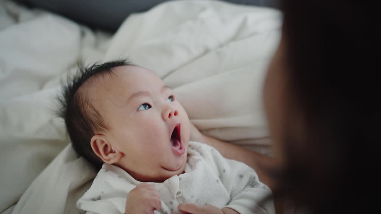 靠近可爱的新生婴儿婴儿女孩在家里早上在床上打哈欠，家庭，孩子，父母，童年，生活，爱的概念视频素材