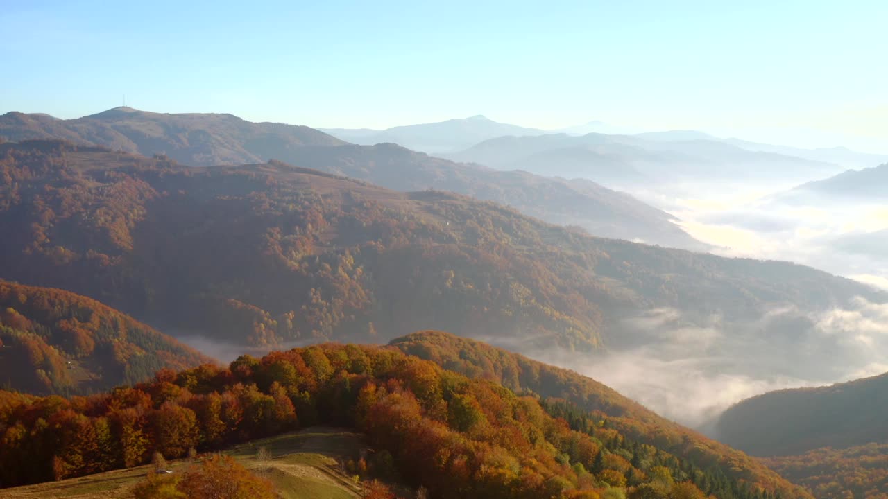 在一个阳光明媚的日子里，一架无人机飞过风景如画的秋山。视频素材