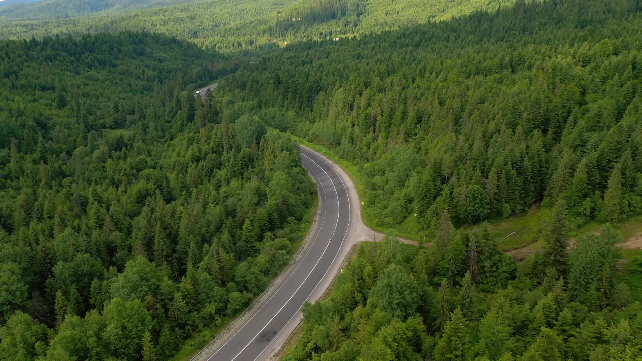 从鸟瞰的角度拍摄一条穿过树林的蜿蜒道路。视频素材