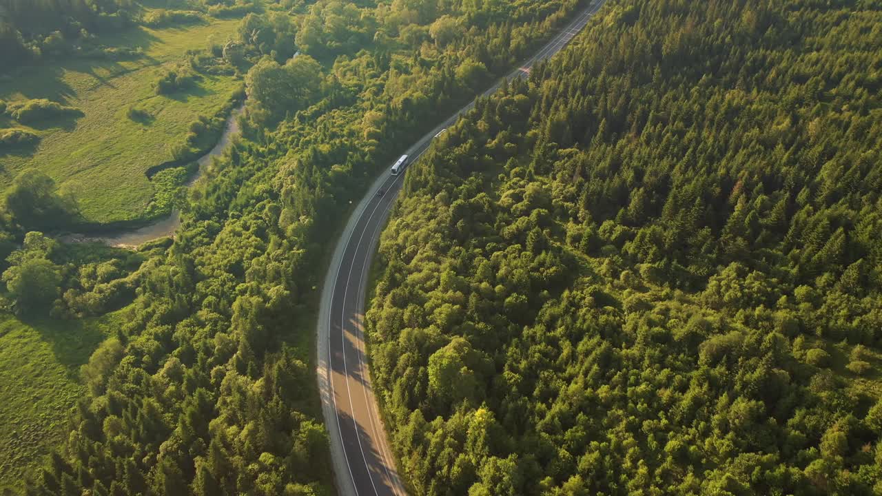 从鸟瞰的角度拍摄一条穿过树林的蜿蜒道路。视频素材