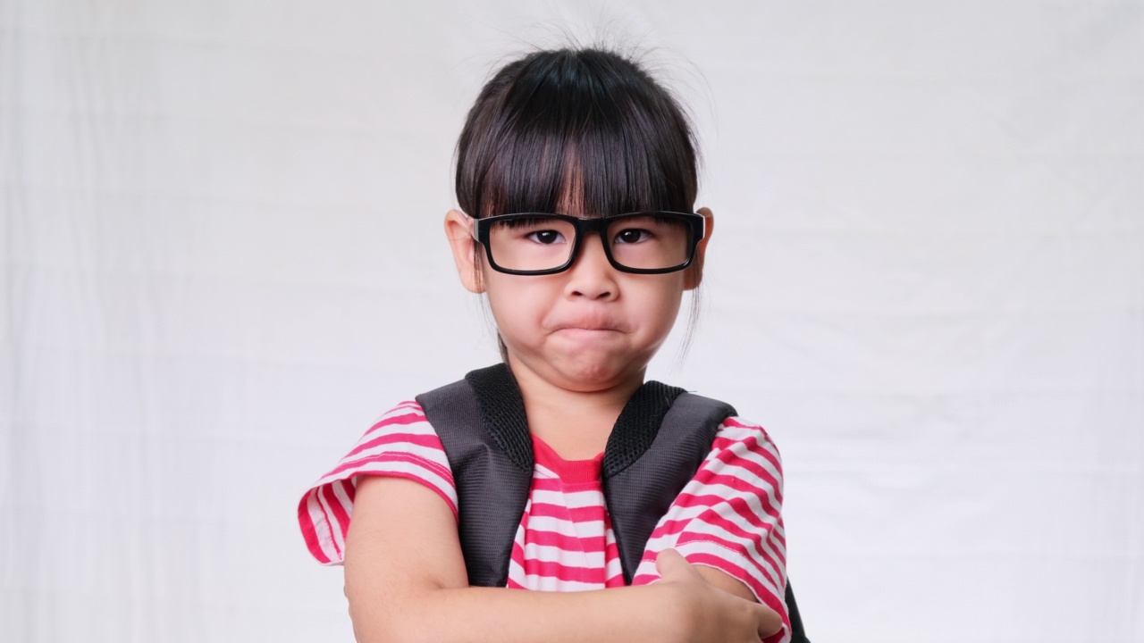 一个沮丧的女学生双手交叉站着，看着镜头，不想去学校。回归学校理念视频素材