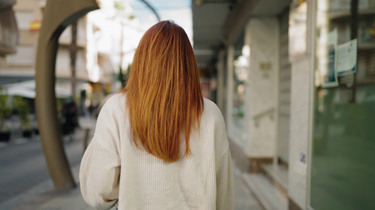 年轻的红发女人自信地微笑着走在街上视频素材