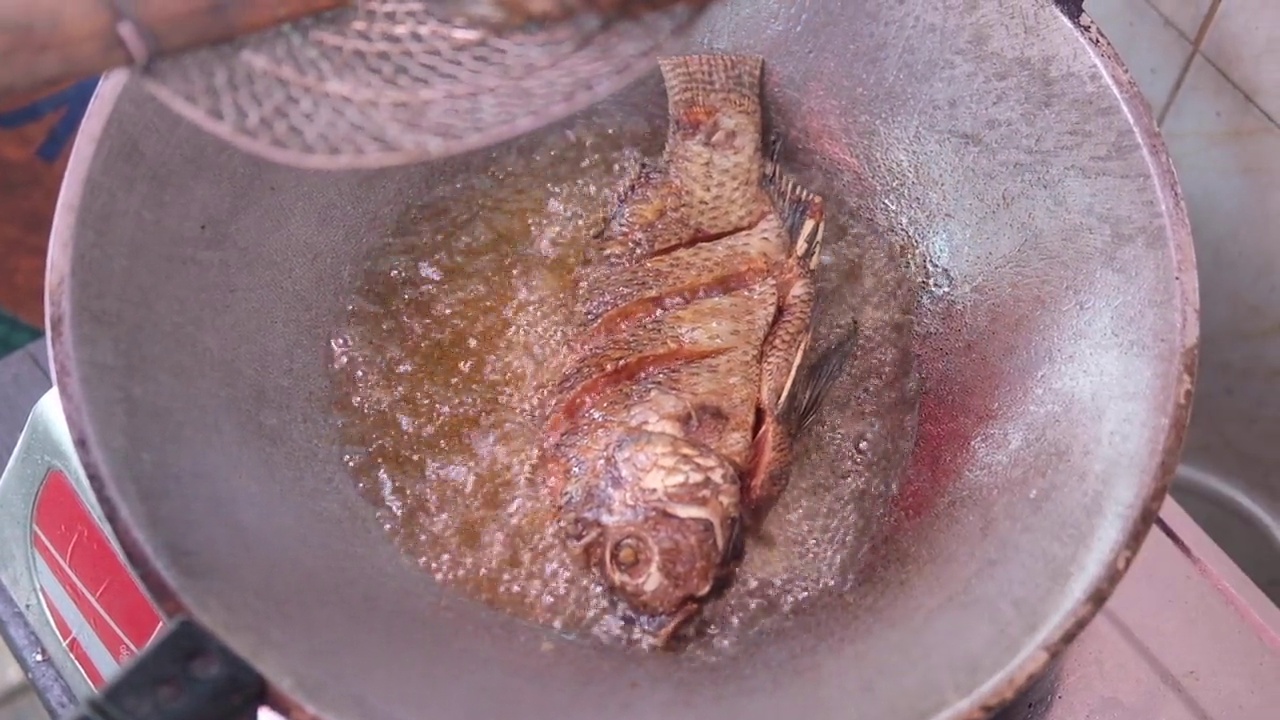 在热油中煎罗非鱼的特写镜头。自制食物的概念视频素材