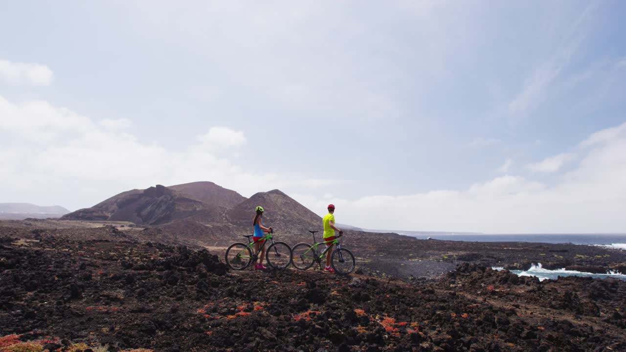 山地自行车MTB骑自行车的女人和男人休息，在自行车道骑车。西班牙，加那利群岛，兰萨罗特，骑着自行车的山地自行车夫妇，享受健康的生活方式视频素材