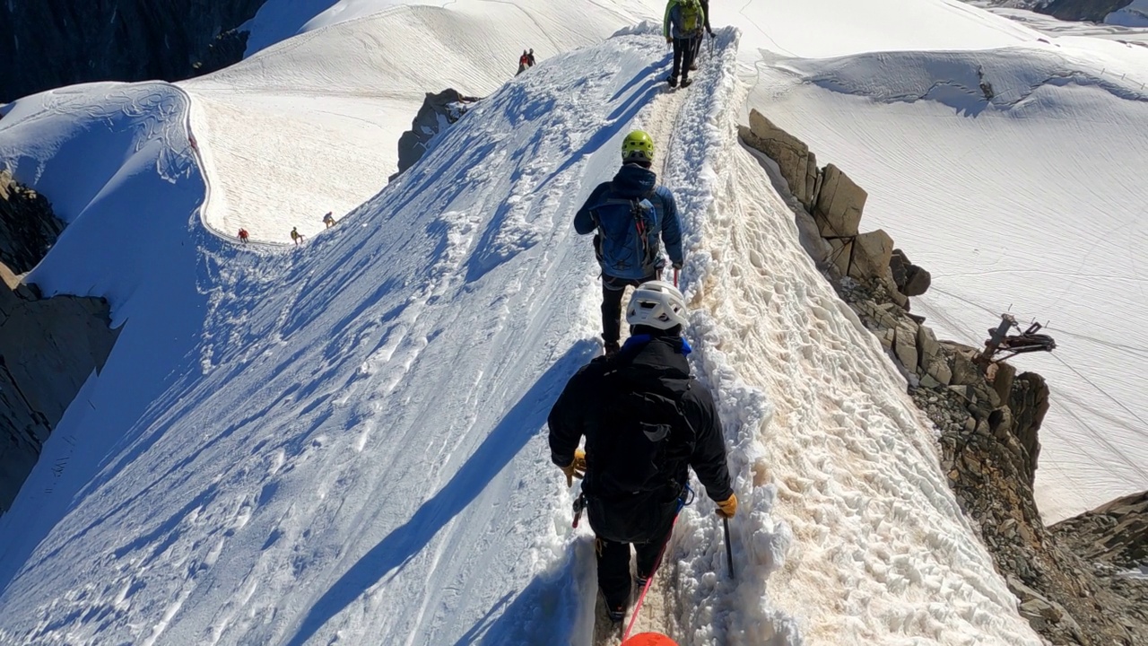 一队登山者正在攀登欧洲阿尔卑斯山的雪峰。使用绳索和攀爬设备。鸟瞰图视频素材