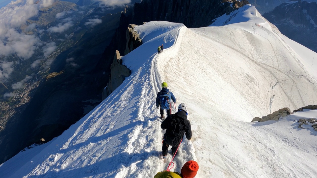 一队登山者正在攀登欧洲阿尔卑斯山的雪峰。使用绳索和攀爬设备。鸟瞰图视频素材