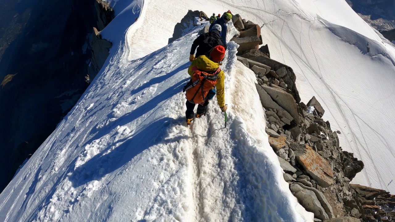 一队登山者正在攀登欧洲阿尔卑斯山的雪峰。使用绳索和攀爬设备。鸟瞰图视频素材