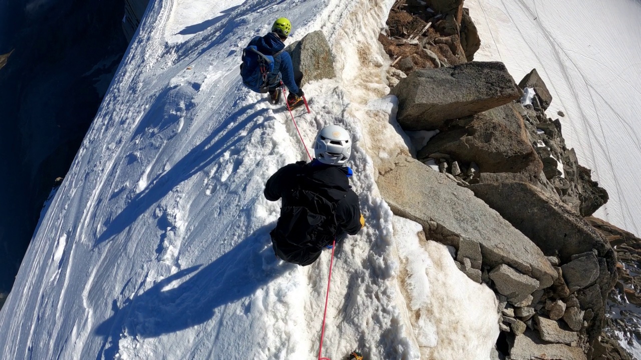 一队登山者正在攀登欧洲阿尔卑斯山的雪峰。使用绳索和攀爬设备。鸟瞰图视频素材