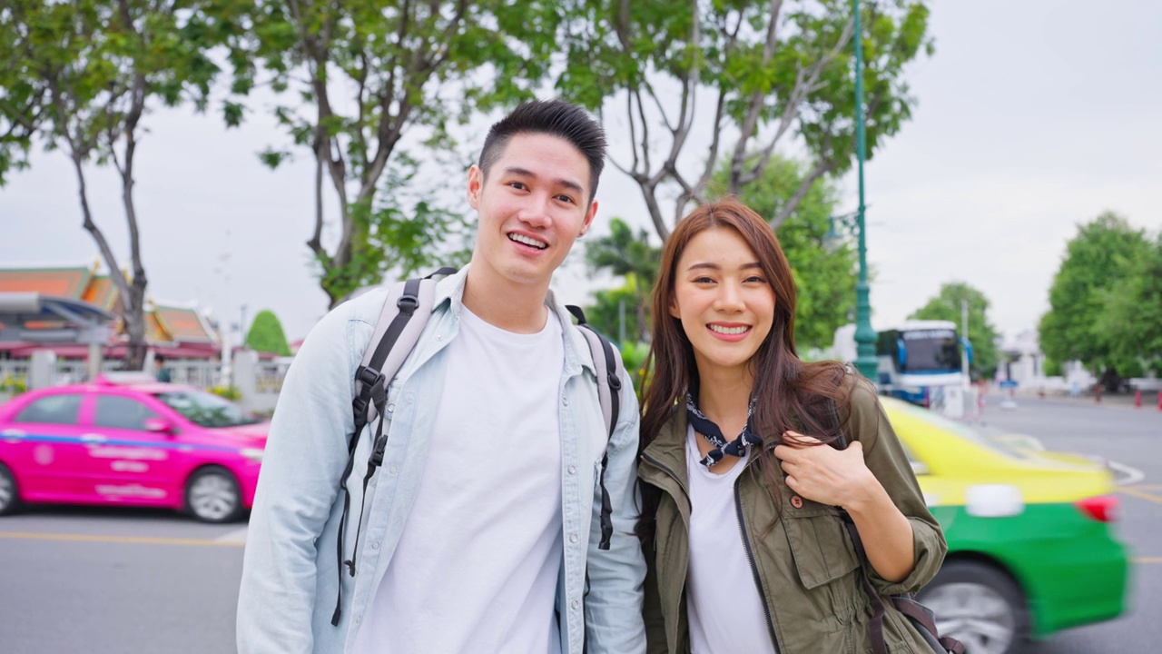 亚洲年轻夫妇在城市度蜜月旅行的写真新婚男女背包客在泰国，手挽着手，看着相机，一起享受假期。视频素材