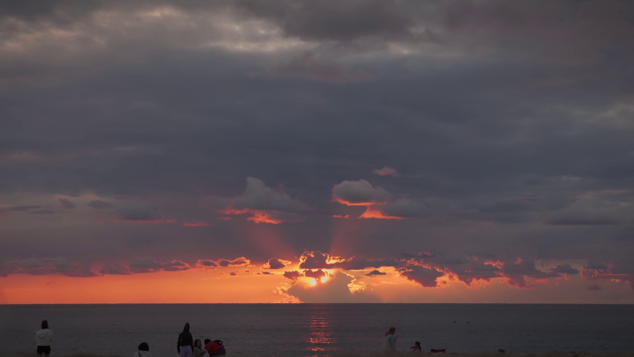 夕阳落在平静的海面上。粉红色橙色的海上日落和壮观的天空。人们在海滩上放松，看美丽的日落。休闲娱乐概念。度假及度假概念视频素材