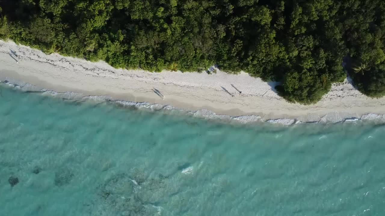 海浪拍打着热带岛屿海滩的无人机天线视频素材