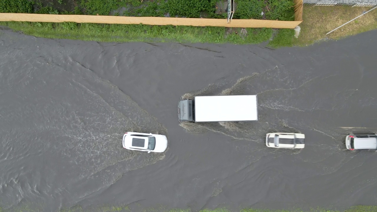 城市交通鸟瞰图，汽车行驶在暴雨后被淹没的街道上。道路排水系统的问题。视频素材