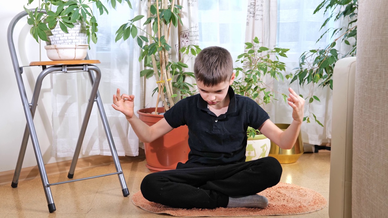 小男孩在练瑜伽，莲花坐姿，室内全身。瑜伽孩子在冥想视频素材