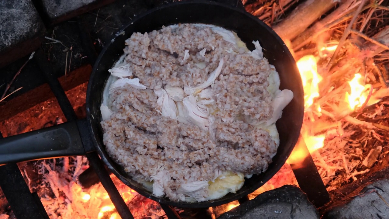 用鸡肉煮鸡蛋，用旅游营火煎锅煮粥，自然视频素材