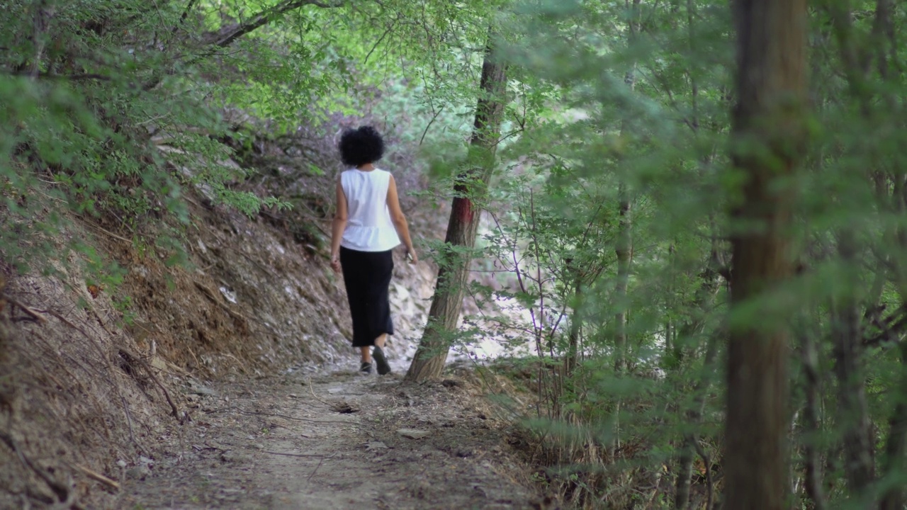 卷头发的女人在森林里徒步旅行视频素材