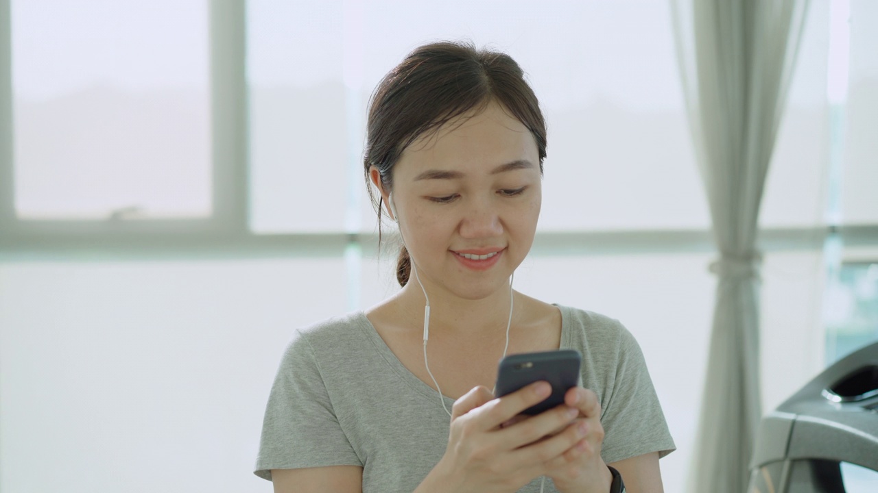 女子在放松运动时用智能手机聊天。视频素材