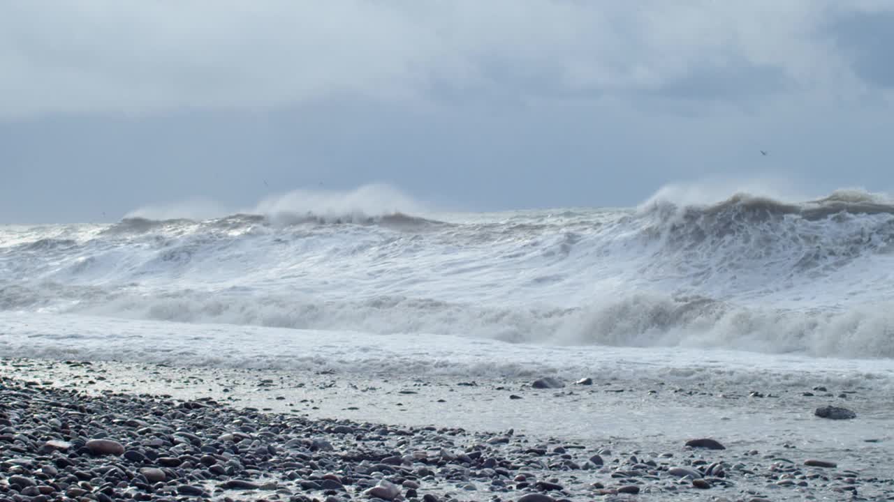 巨大的海浪拍打着海岸，蓝色的海水背景。海上的风暴和巨大的海浪拍打成海洋飞溅的泡沫。刮风坏天气慢动作视频素材