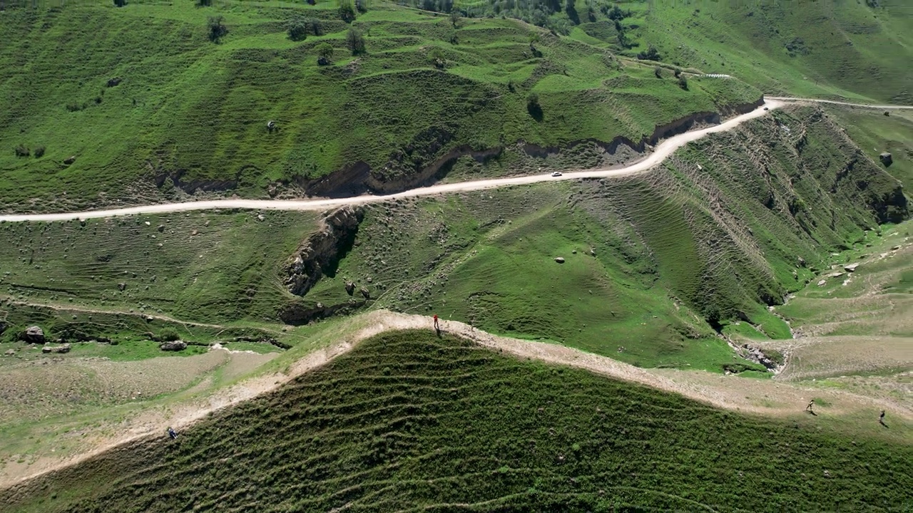 游客在绿色山谷的夏季草地上徒步旅行，鸟瞰图。行动。人们行走在绿油油的夏山山顶，有旅行和冒险的概念视频素材