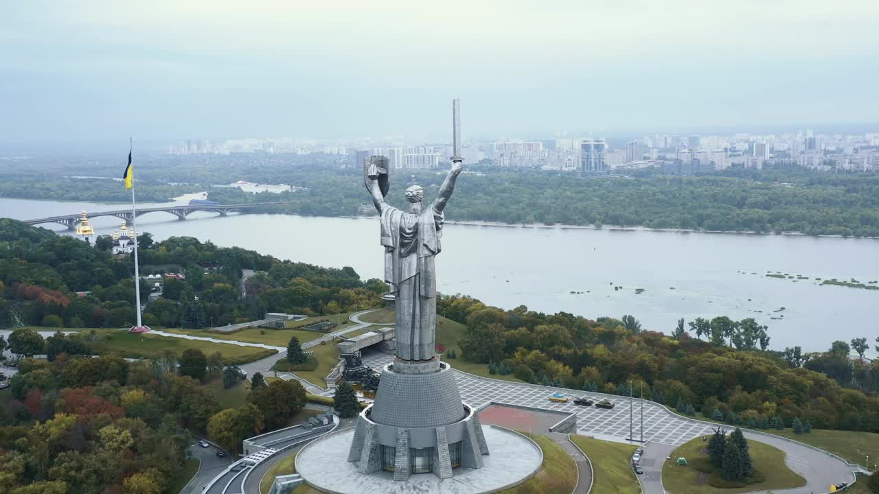 宽广的航拍祖国纪念碑和乌克兰国旗在基辅和平的夏天第聂伯河全景。视频素材