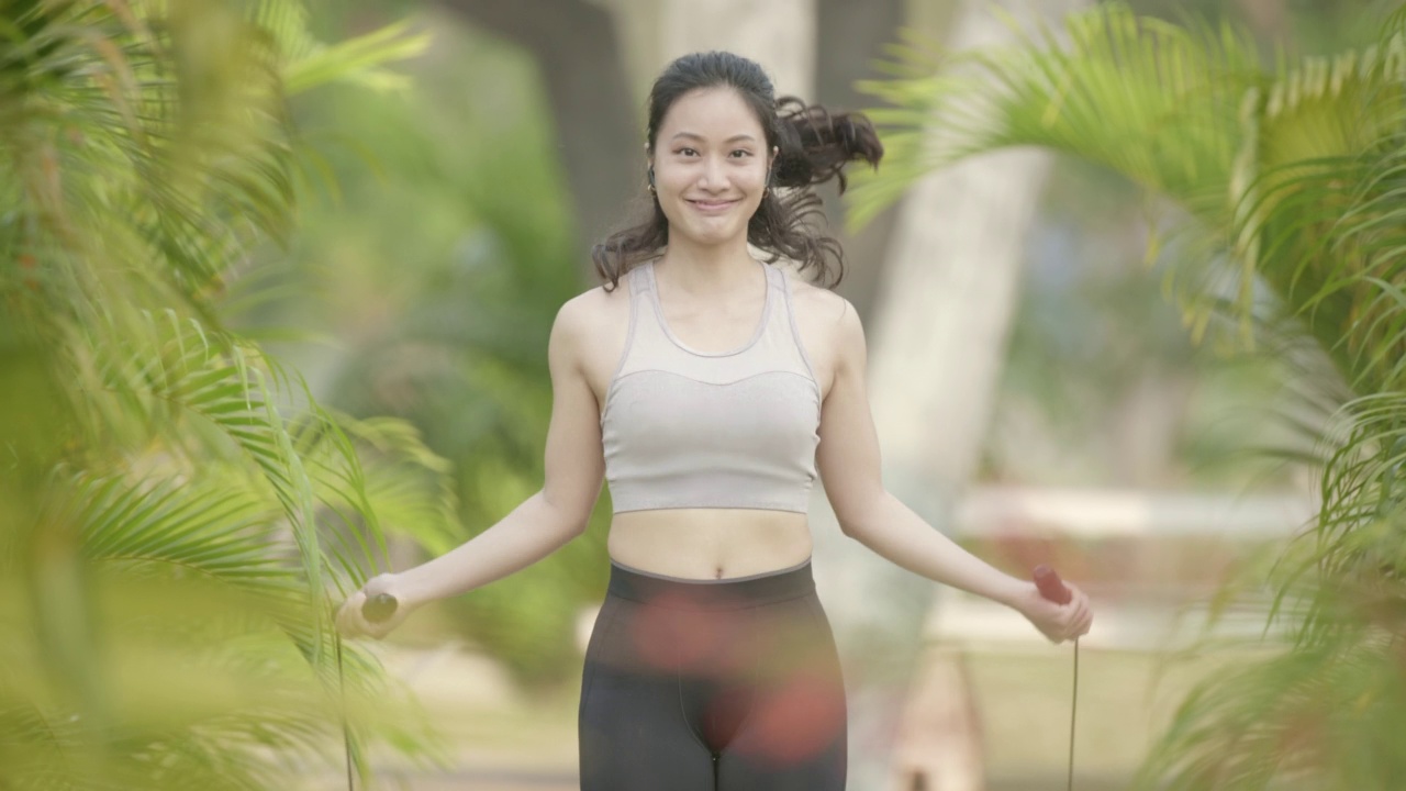 亚洲女性用跳绳练习有氧运动减肥的场景。视频素材