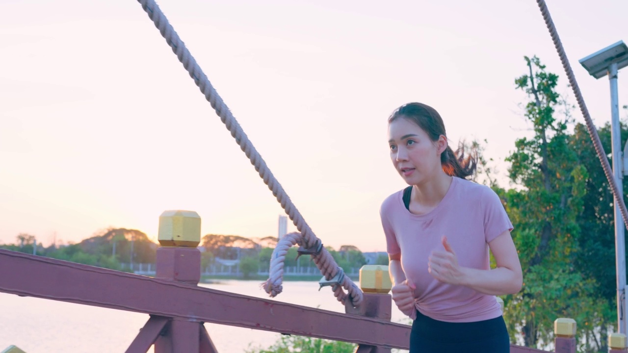 亚洲年轻美丽的运动女子在公园的街道上跑步。美丽的运动员和坚定的女孩在运动服装锻炼慢跑锻炼户外保健在傍晚日落在花园。视频素材