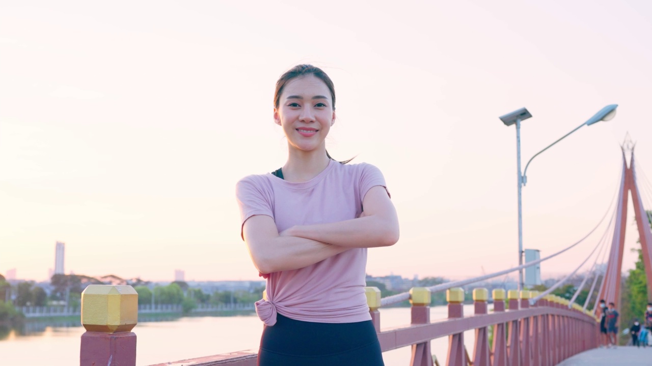 亚洲积极运动的女性在户外运动后站在自信。美丽的女孩穿着运动服微笑的肖像，在晚上在公园跑步健身后看着相机。视频素材