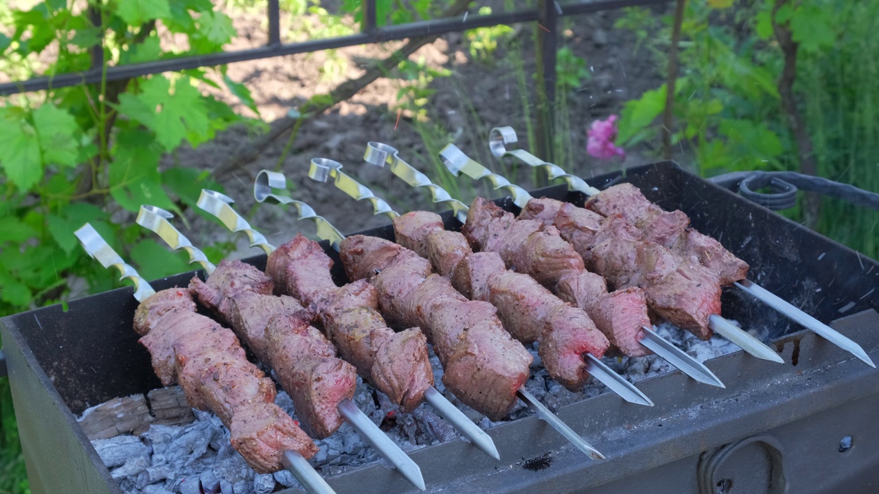 户外烧烤用金属串和蔬菜。传统的东方菜肴，腌制的烤肉，在木炭和火焰上烧烤。烤猪肉，羊肉，烤肉串，烤肉串。街头食品视频素材