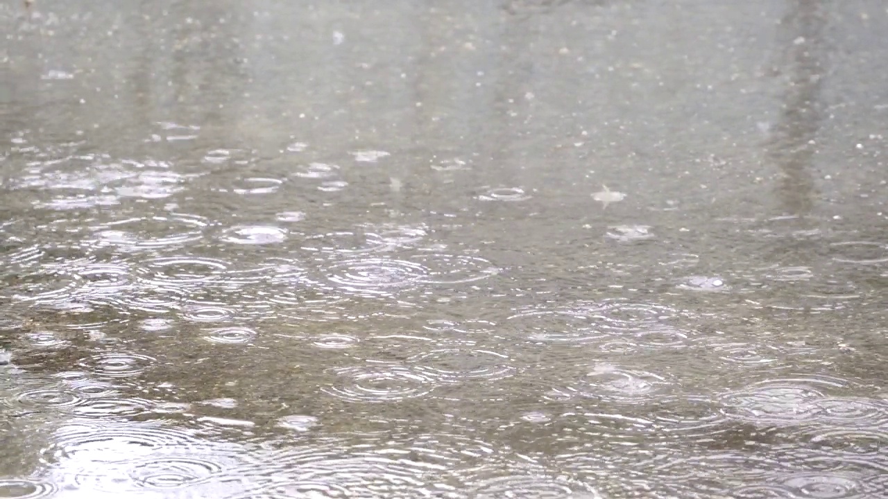 雨水落在沥青地上的水坑里。雨滴落在路上。由于大雨道路被淹了视频素材